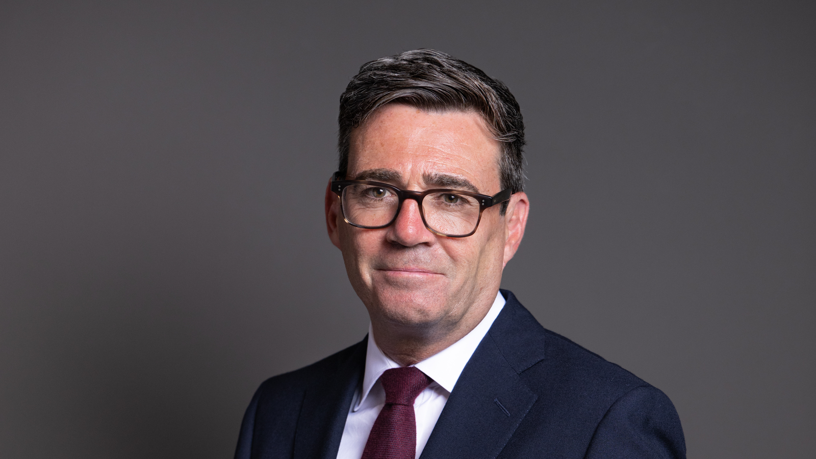 Archive official portrait of Andy Burnham in a dark suit against a grey background, photographed 13 July 2026.