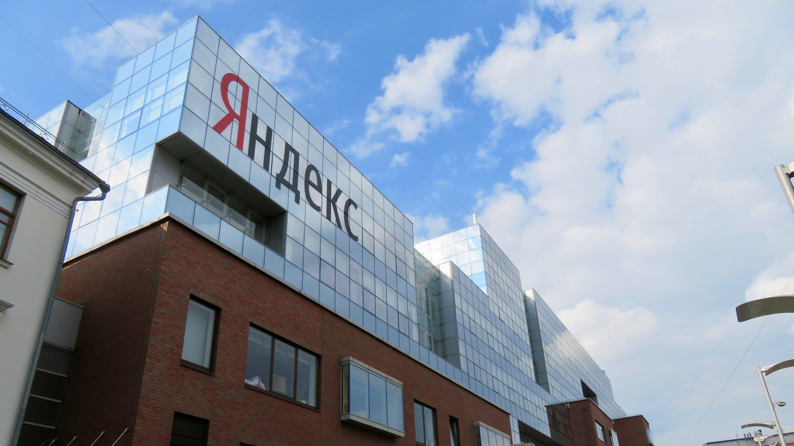 Archive photograph from 2019 of Yandex’s Moscow office, showing its large Cyrillic company sign on a glass-and-brick facade under a blue sky. Representative office image, not an attacked data centre.